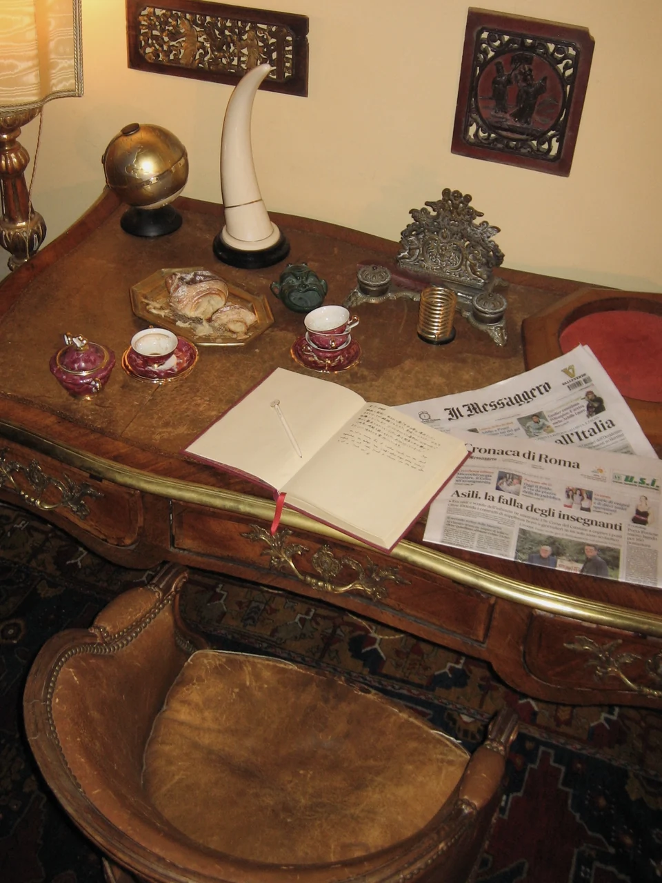 Coffee, pastries, an open notebook and a newspaper on the antique desk at Giordano Segreto